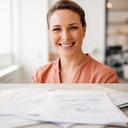 A West Haven real estate agency owner smiling in a bright office with signed paperwork on the desk